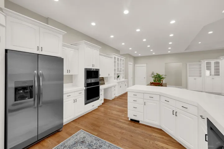 Expansive kitchen featuring white cabinetry, light-toned countertops, and wood-finish flooring