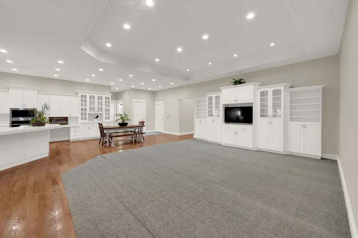 Expansive open-concept living space featuring a built-in entertainment center, recessed lighting, and crown molding