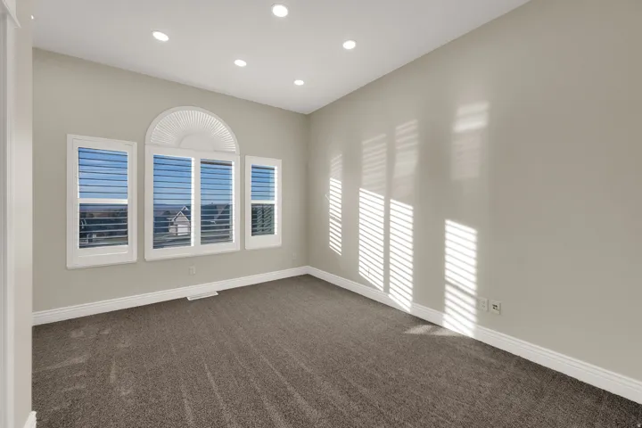Spacious room featuring multiple windows with integrated plantation shutters, recessed lighting, neutral wall tones, and carpet flooring