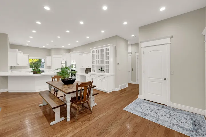 Expansive open-concept space featuring wood-finish flooring, recessed lighting, white cabinetry, and white countertops