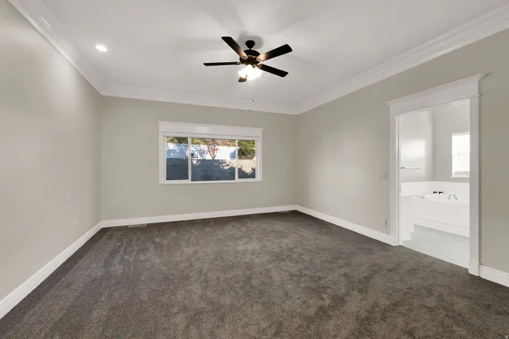 Spacious room featuring gray carpet flooring, a ceiling fan with light fixture, recessed lighting, and white crown molding