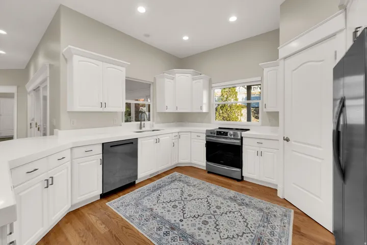 Spacious kitchen featuring white cabinetry, light-toned countertops, and wood-finish flooring