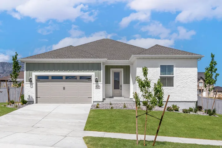 Modern ranch-style residence featuring a two-car garage with transom windows, a white brick facade, and green vertical siding accents