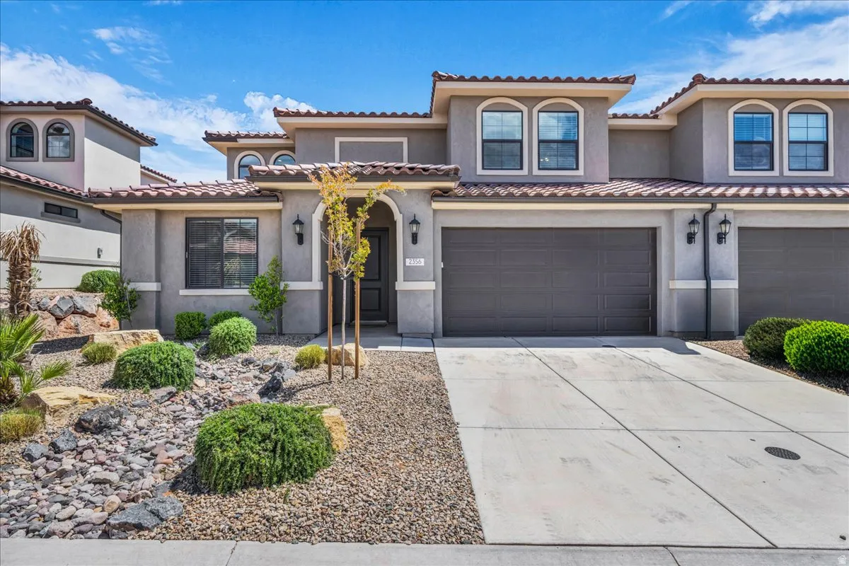 Stucco exterior with arched entry, two-car garage, and desert-inspired landscaping