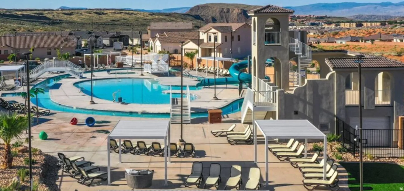 Expansive aquatic facility featuring a large swimming pool with a distinct lazy river, a multi-story waterslide structure, and multiple shaded lounging areas