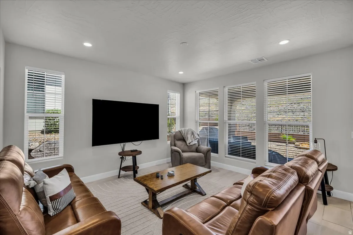 Spacious living area featuring light-toned walls, recessed lighting, and multiple windows with white blinds