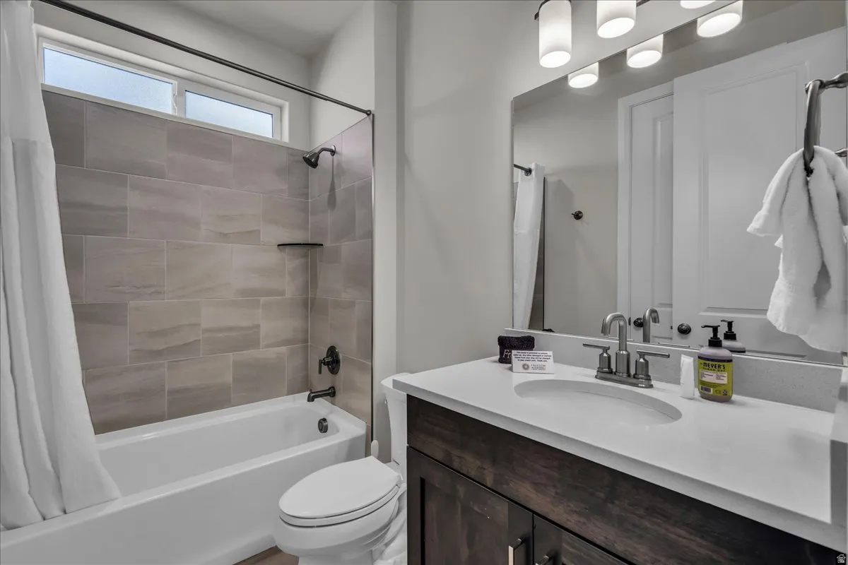 Bathroom featuring a white vanity with a light-toned countertop, a rectangular undermount sink, and a mirrored wall