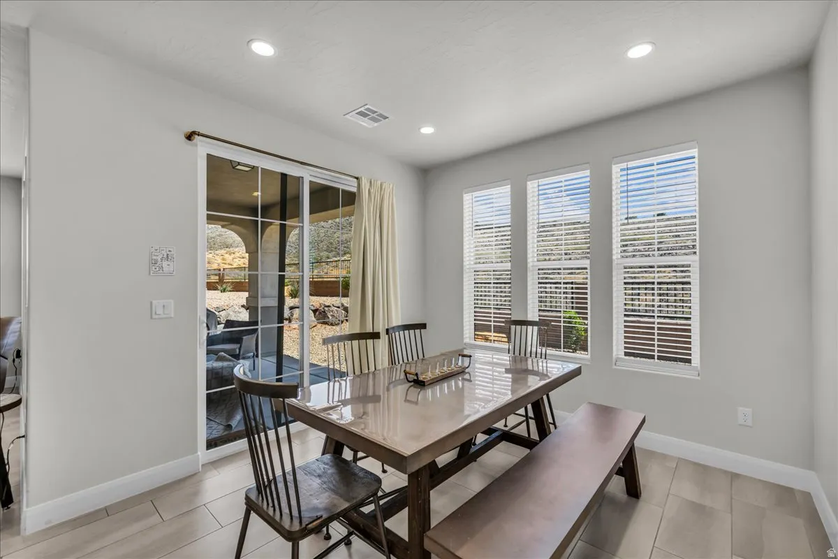 Dining area featuring multiple windows with blinds, recessed lighting, a sliding glass door, and tile flooring