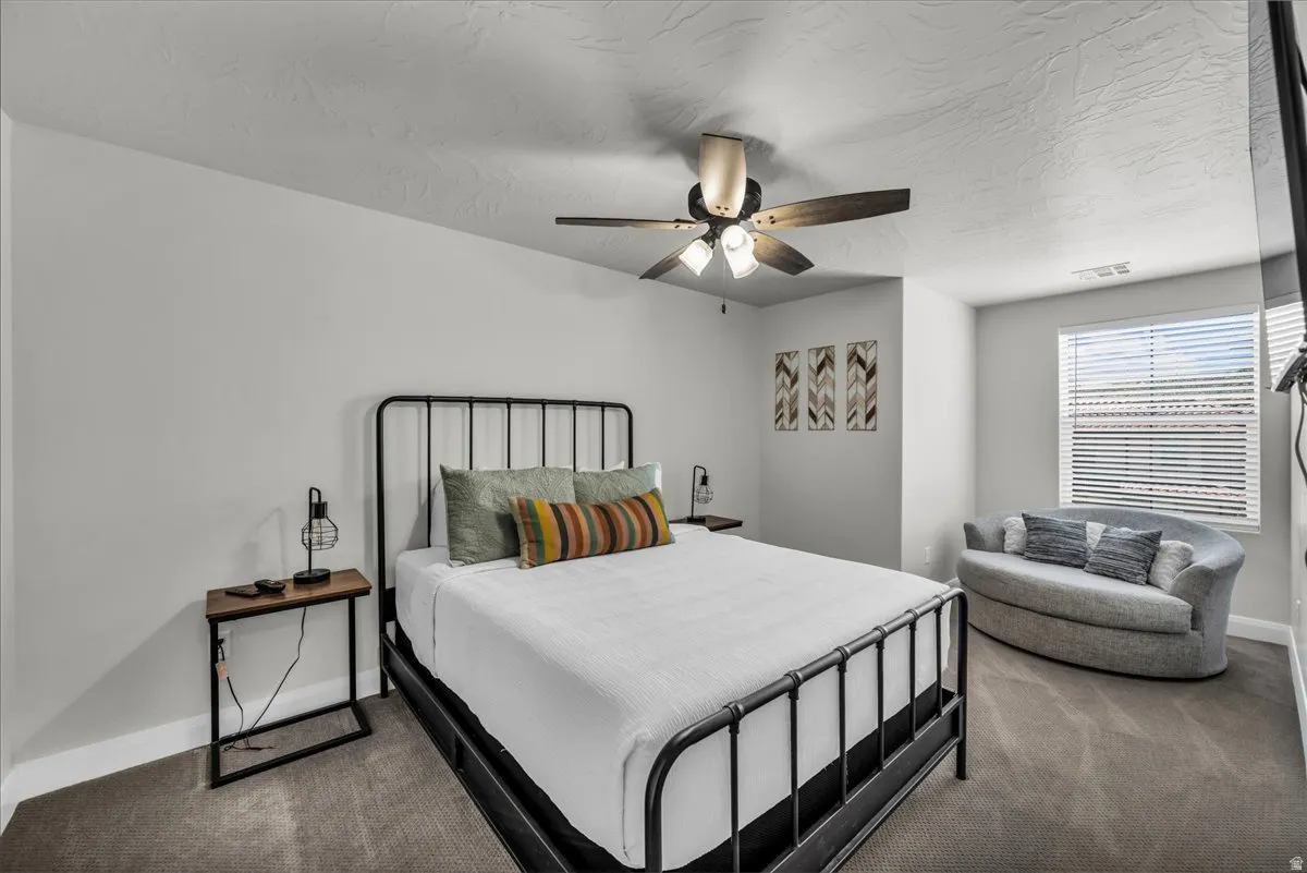 Carpeted room featuring a ceiling fan with integrated lighting, a large window with blinds, and light gray painted walls