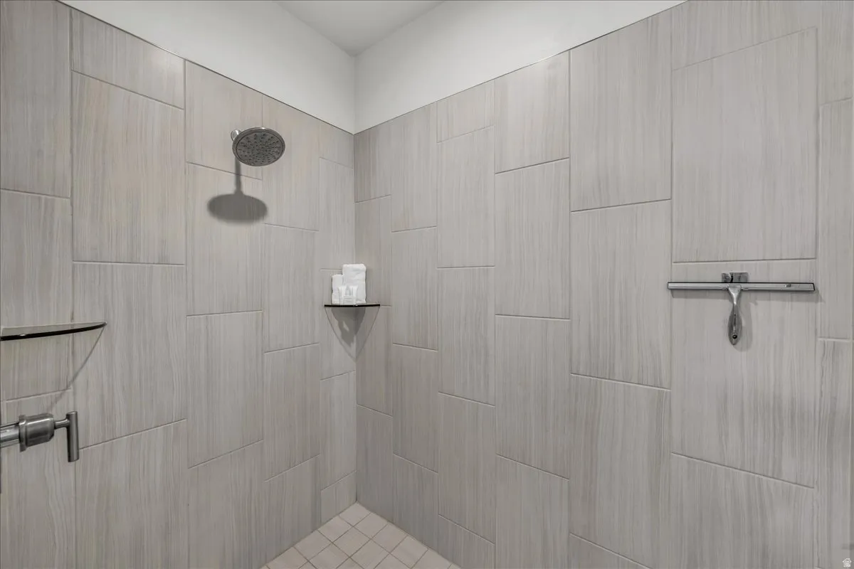 Shower enclosure with light grey wood-look tile walls and a hexagonal tile floor