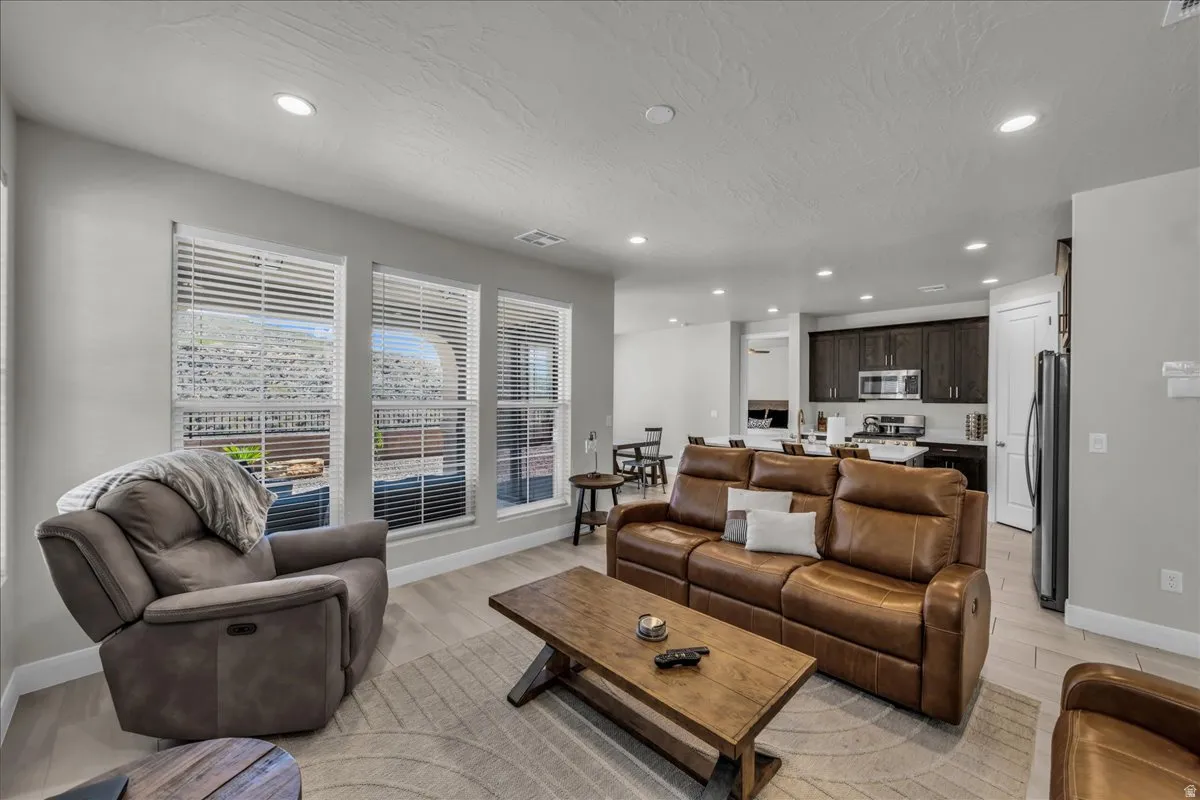 Open-concept living area with wood-finish flooring, recessed lighting, and ample natural light from multiple windows