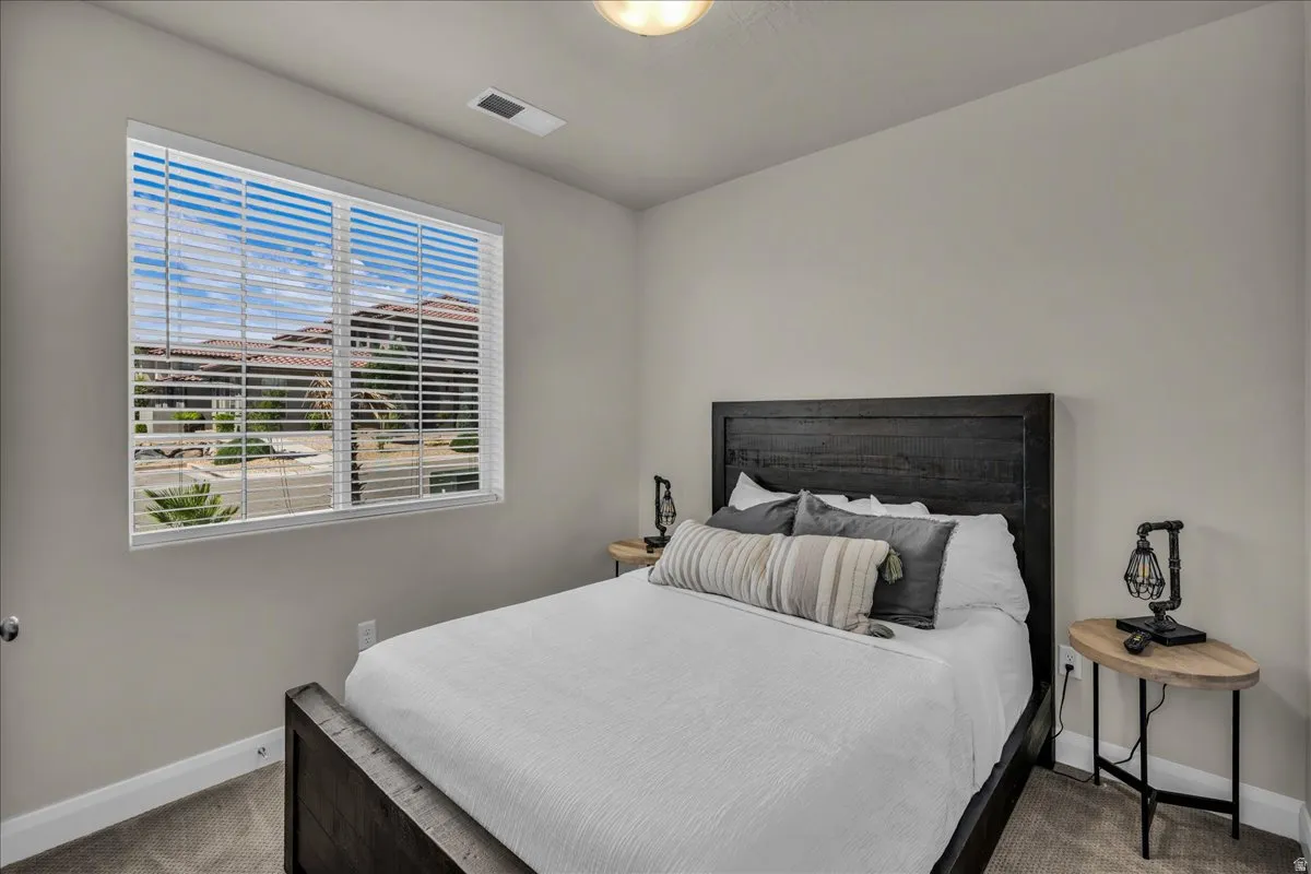 Bedroom featuring a large window with horizontal blinds, neutral wall paint, and carpeted flooring