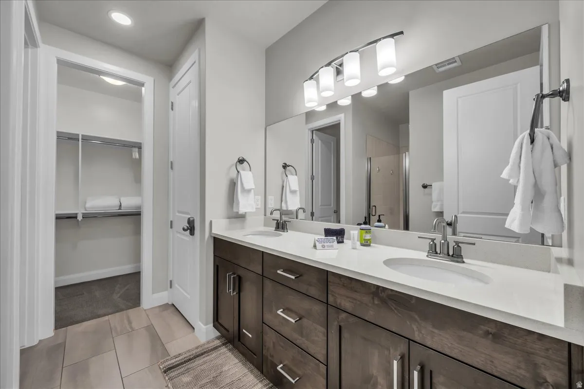 Bathroom featuring a double vanity with stone countertops, dark wood-finish cabinetry, and brushed nickel fixtures