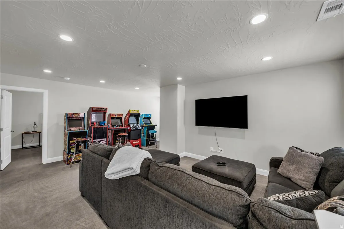 Spacious recreational room featuring recessed lighting, a mounted television, and a neutral color palette