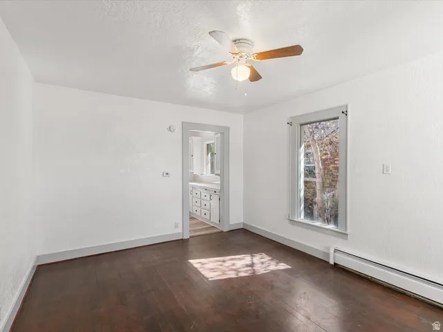 Living area featuring wood-finish flooring, white walls, and a ceiling fan with light fixture