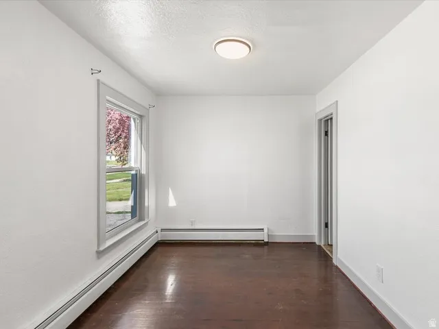Room featuring wood-finish flooring, white walls, and a recessed window