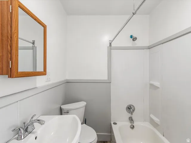 Bathroom featuring a wood-finish medicine cabinet, chrome fixtures, white porcelain sink, and a white bathtub with a shower surround