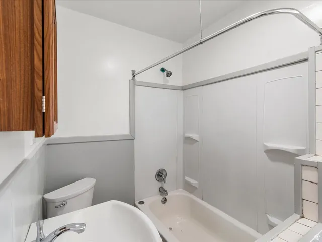 White bathroom featuring a bathtub with an integrated shower, white shower surround, and chrome fixtures