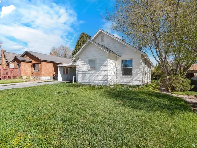 White single-story exterior with a side porch extension and a front lawn