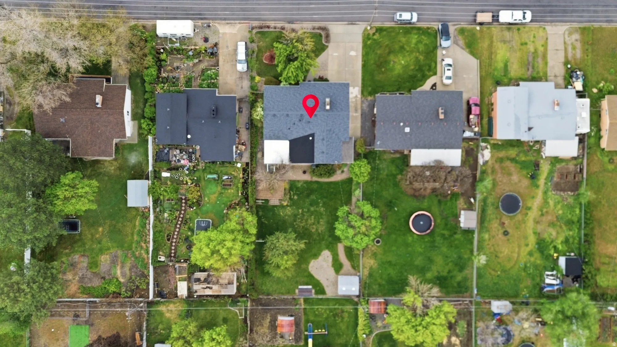 Property featuring a dark shingled roof, a paved driveway, and a spacious backyard with mature trees