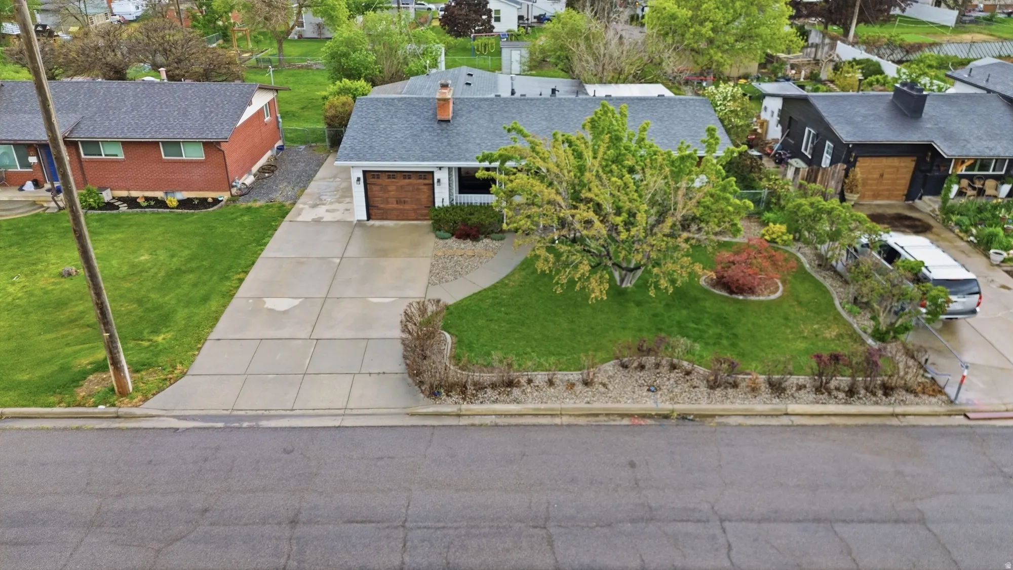 Single-story home featuring a gray shingle roof, attached two-car garage with wood-finish doors, and a concrete driveway
