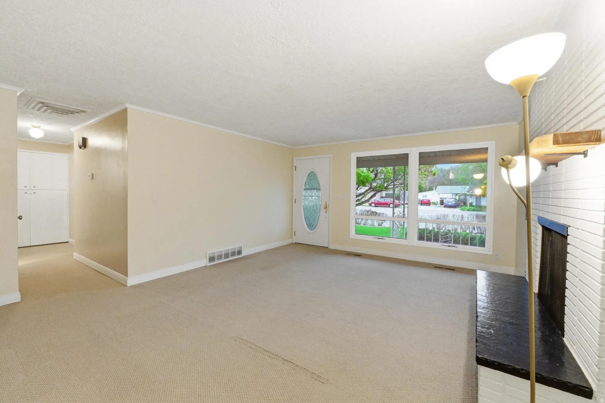 Carpeted room with a white brick fireplace and a dark mantel