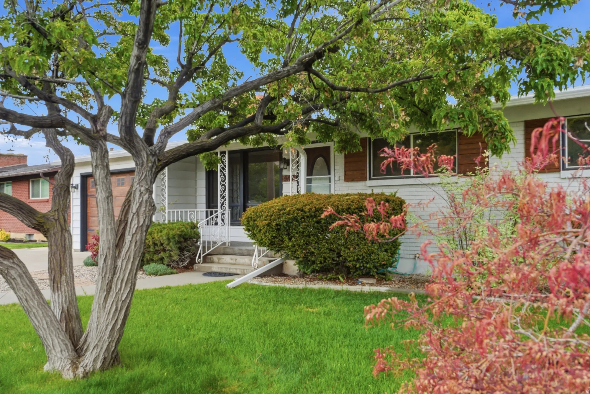 Front exterior featuring white brick siding and dark-framed windows with wood-finish shutters