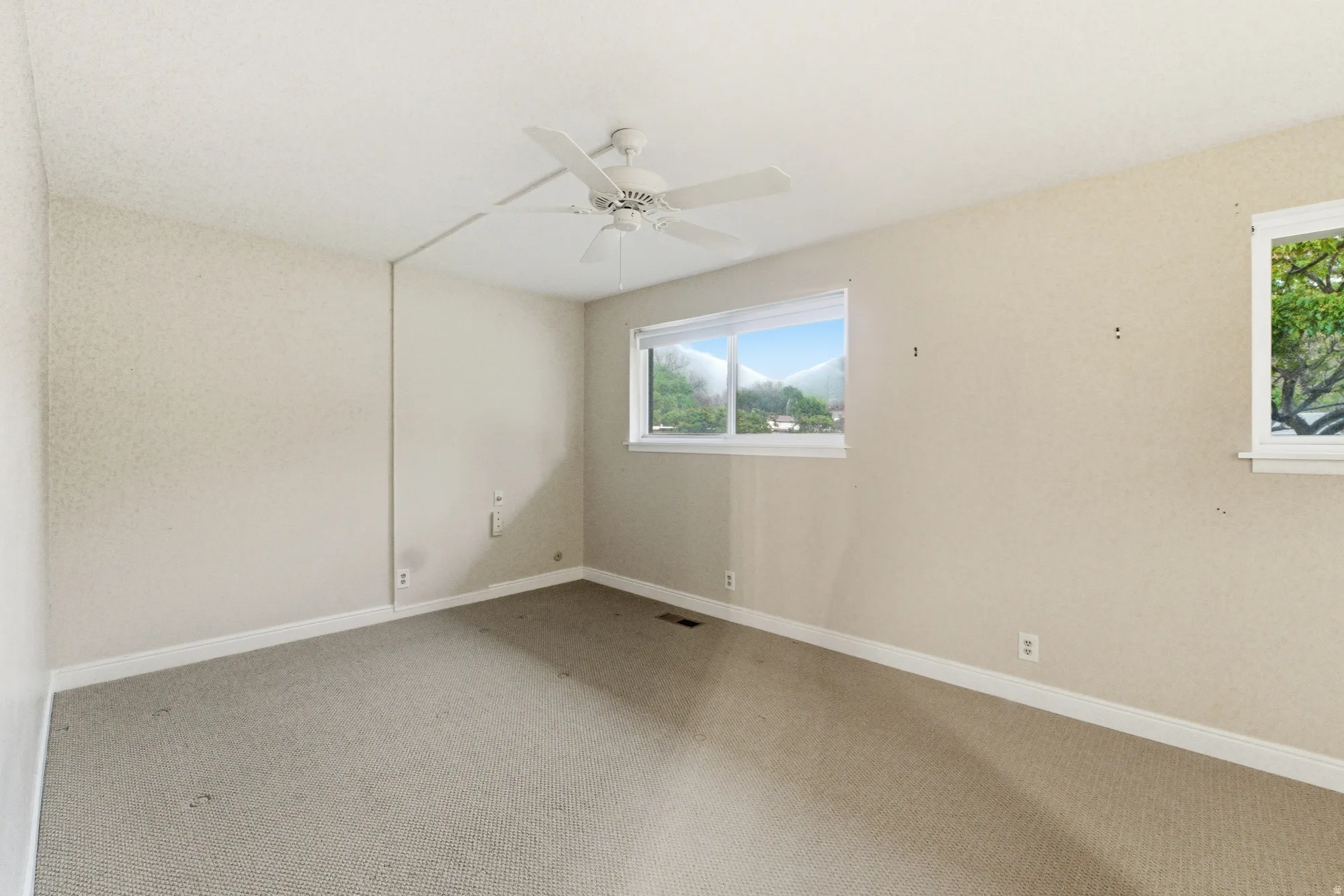 Carpeted room with a ceiling fan