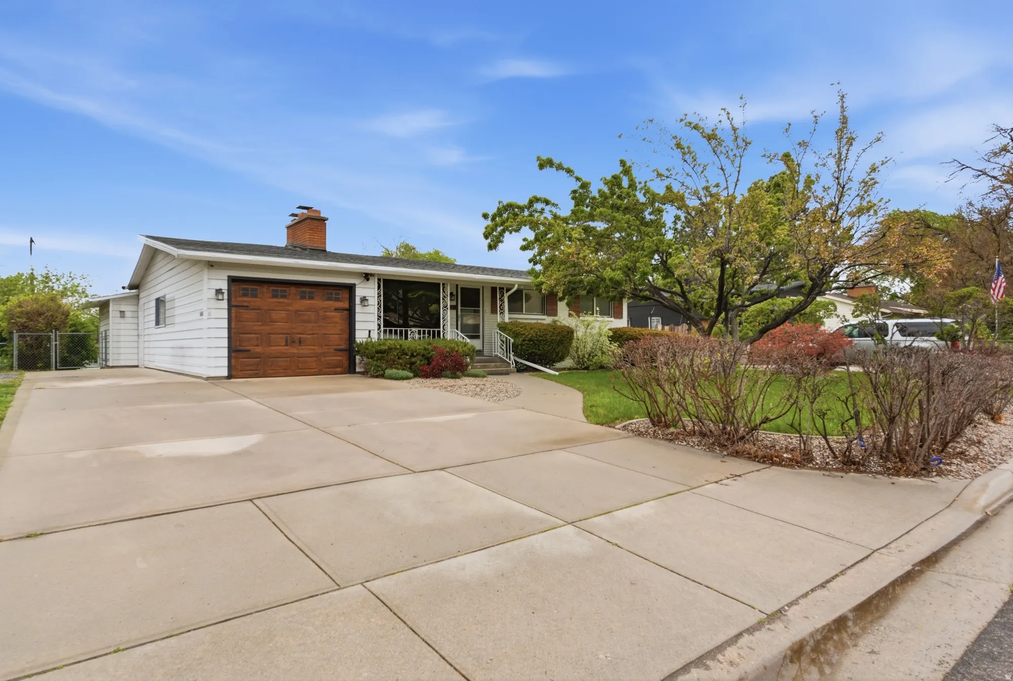 Single-story residence featuring white siding and a wood-finish garage door