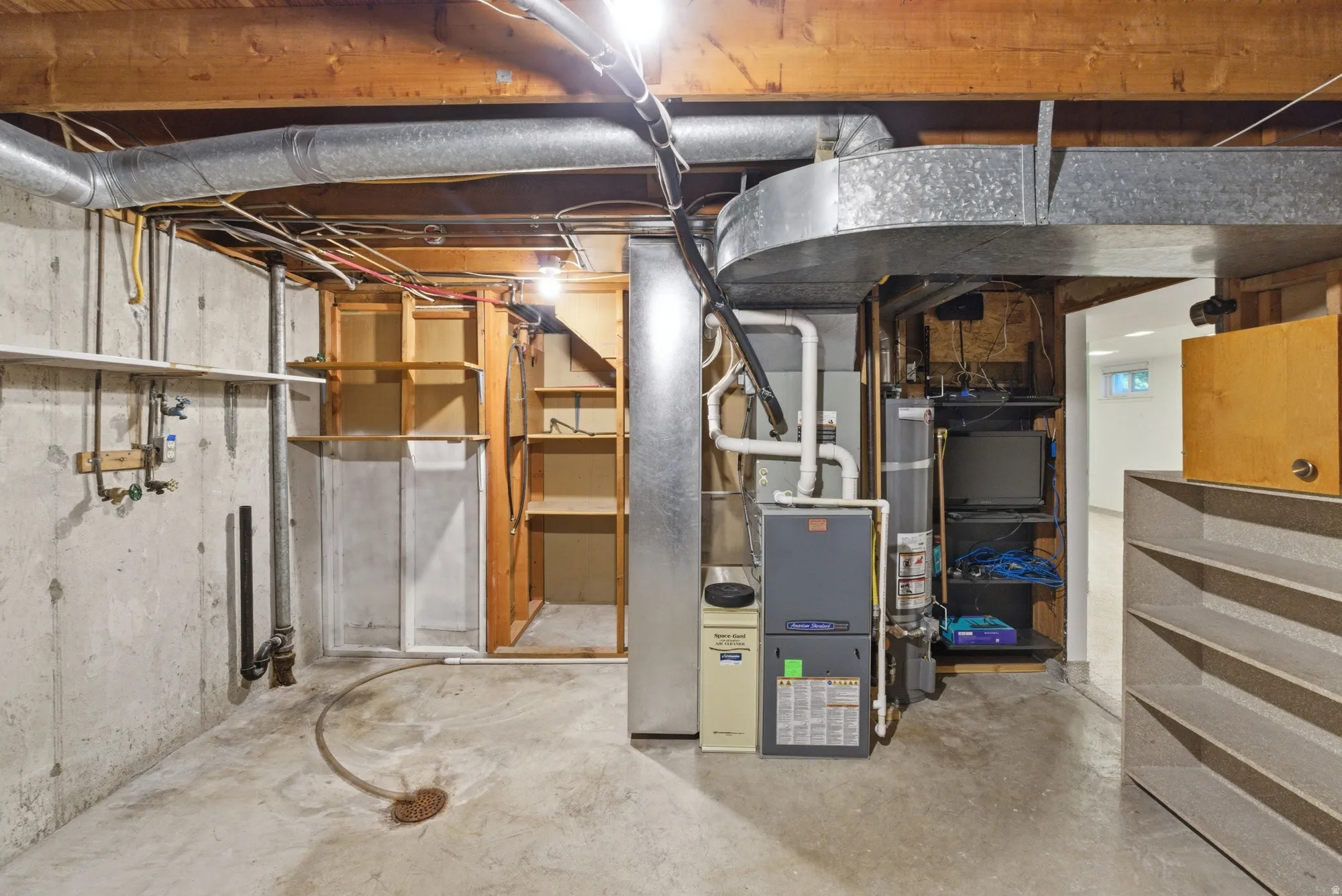 Unfinished basement space featuring a concrete floor, exposed wood ceiling joists, and visible utility systems