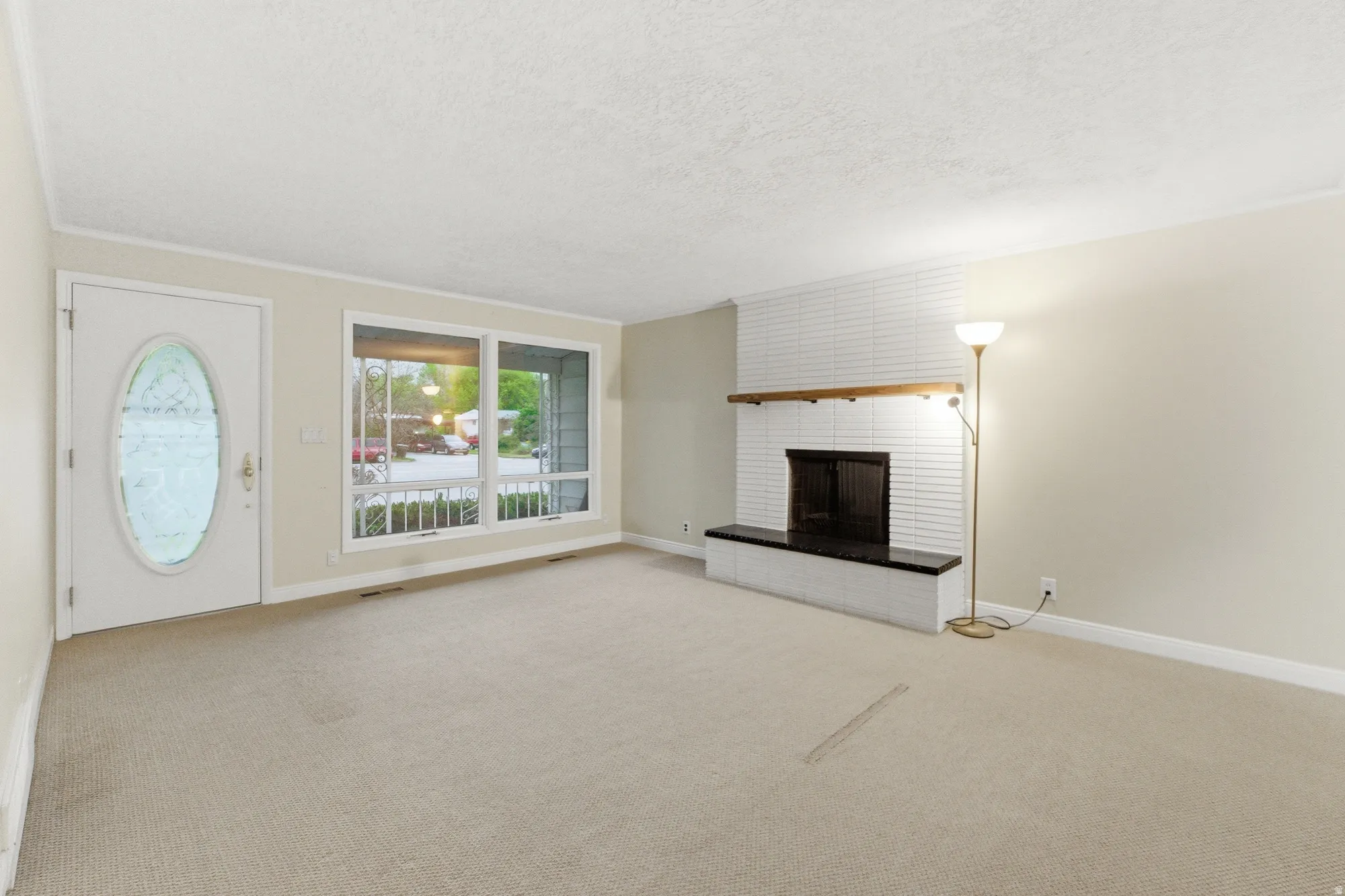 Living space featuring a white brick fireplace with a wood mantle, a dark hearth, and a light-colored carpet