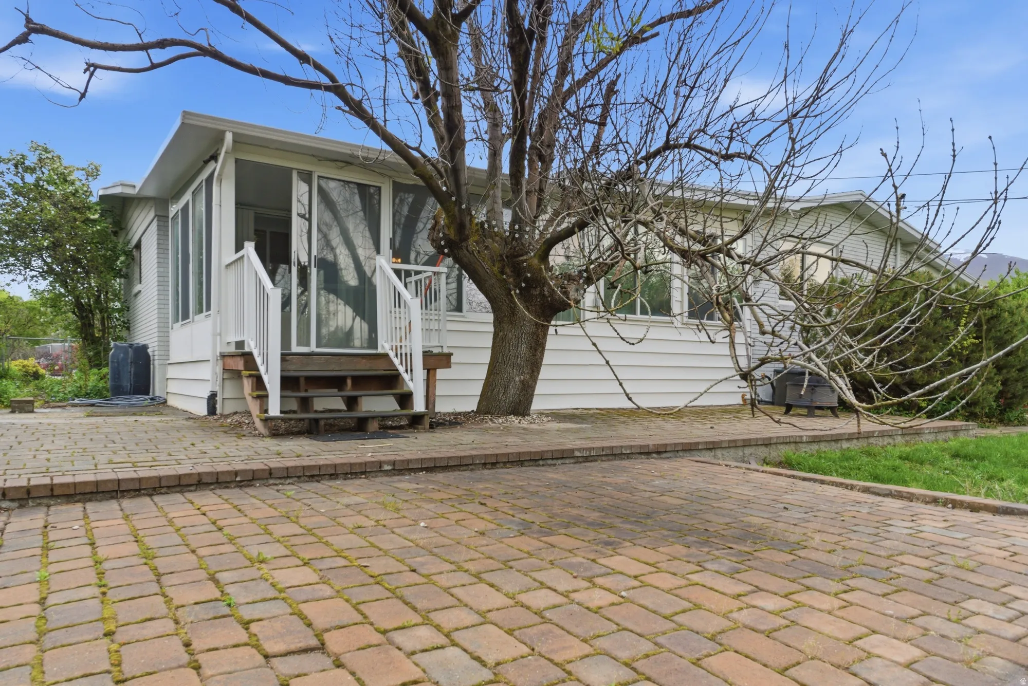 Brick paver patio and walkway with a white-sided exterior