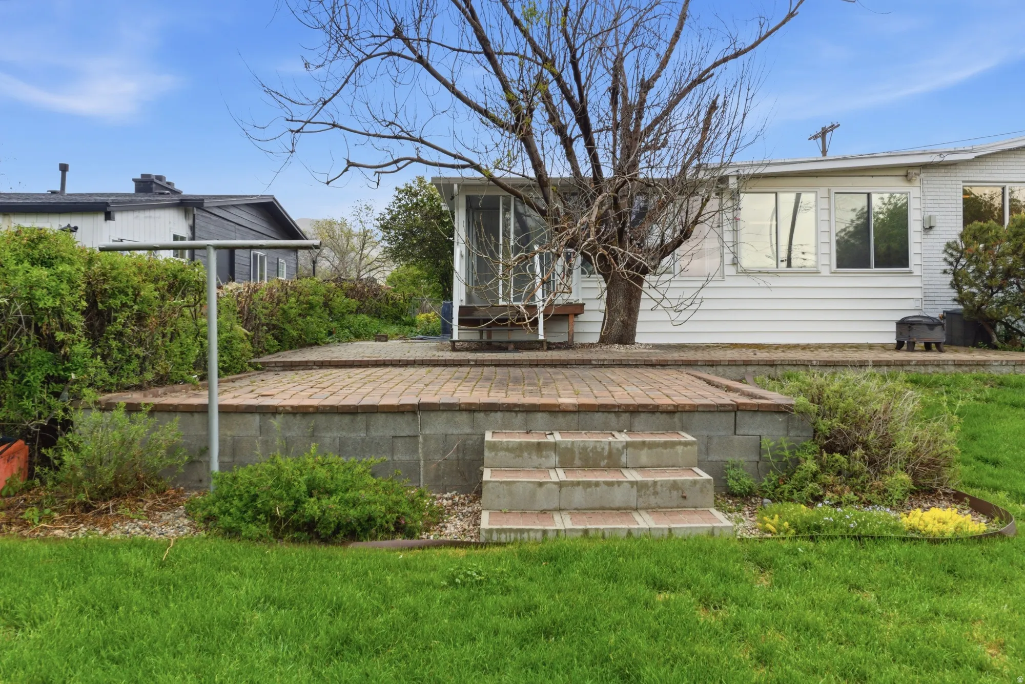 Expansive outdoor patio featuring brick pavers, a block wall retaining structure, and integrated steps