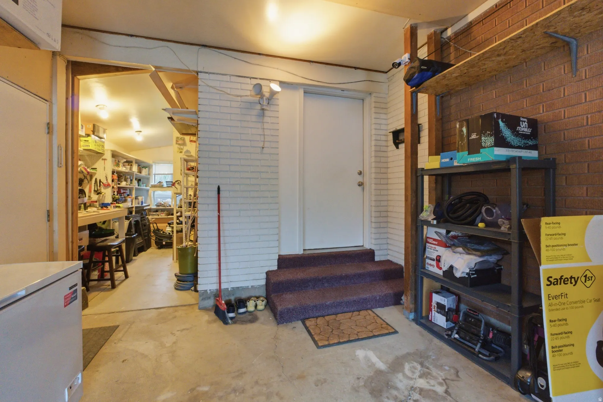 Utility space featuring a concrete floor, exposed brick wall, and built-in shelving