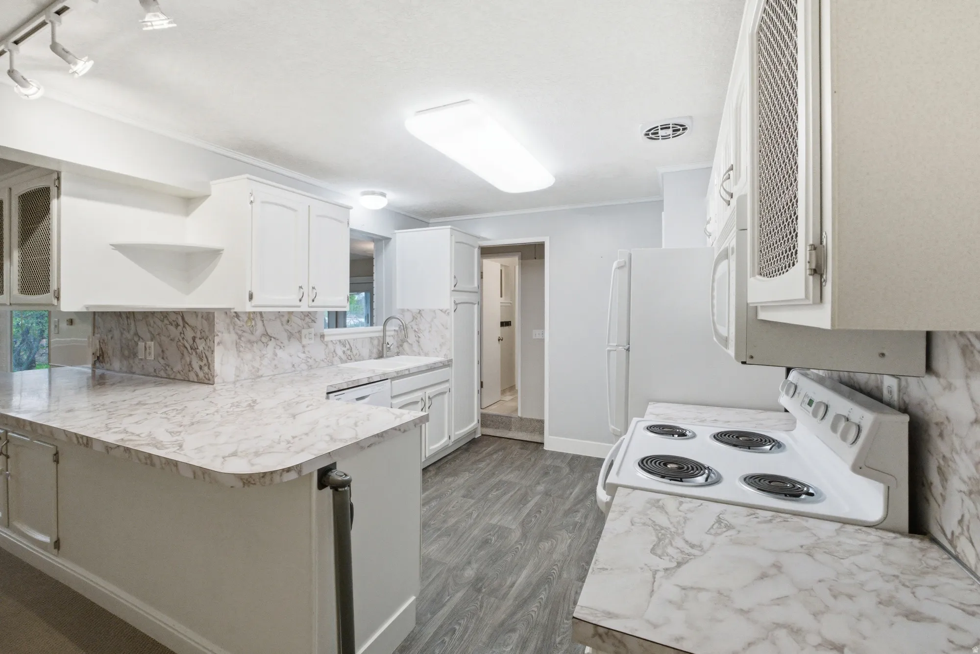 Kitchen featuring extensive counter space with a marble-patterned finish, white cabinetry, a built-in electric range, and wood-finish flooring