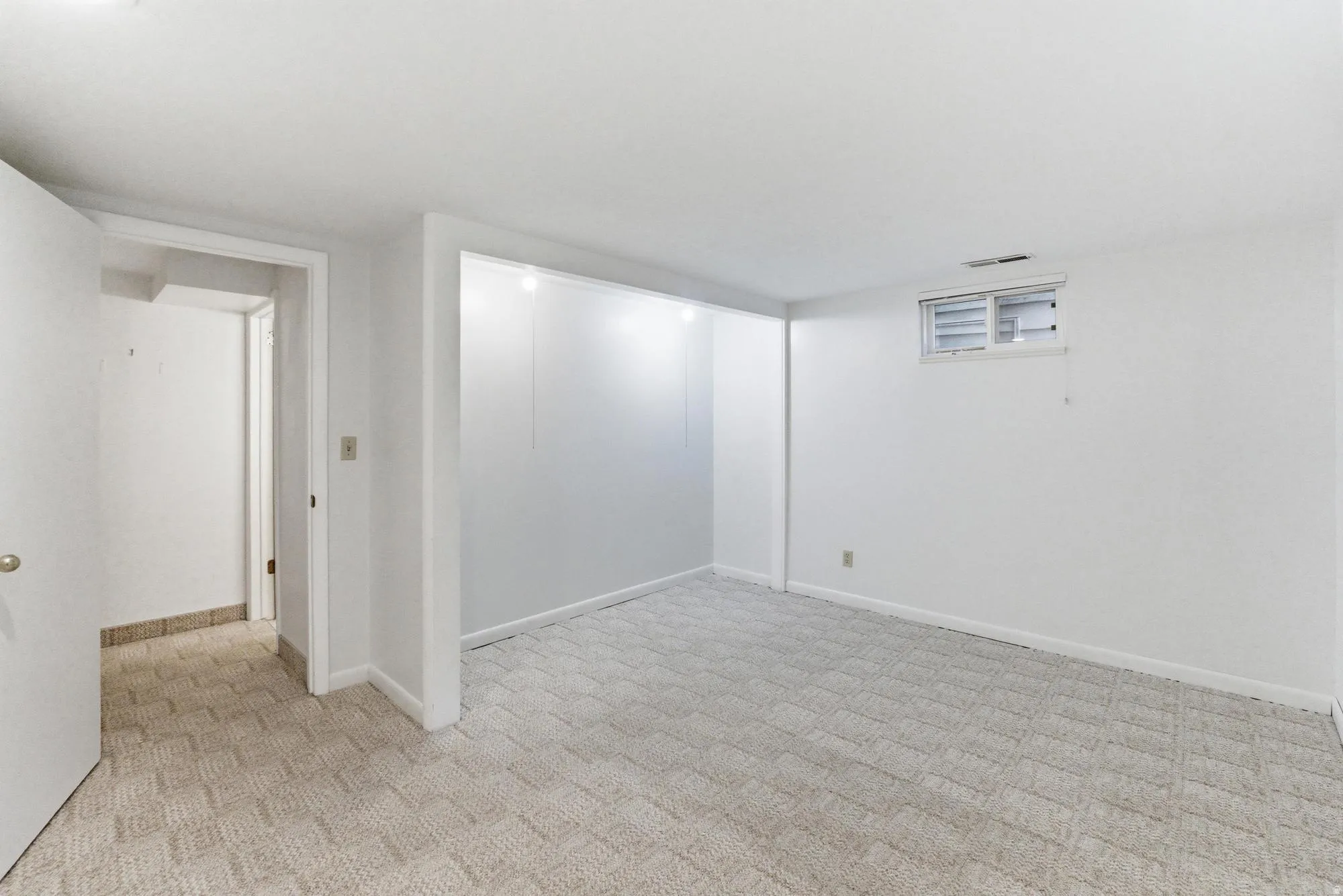 Carpeted room featuring white walls, a single window, and a white interior door