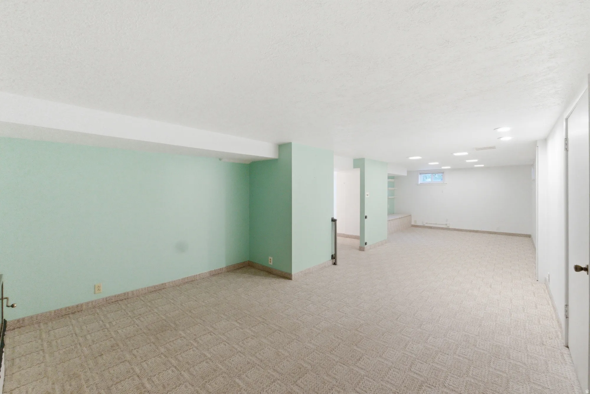 Spacious finished room with light-colored carpeting, recessed lighting, and a window