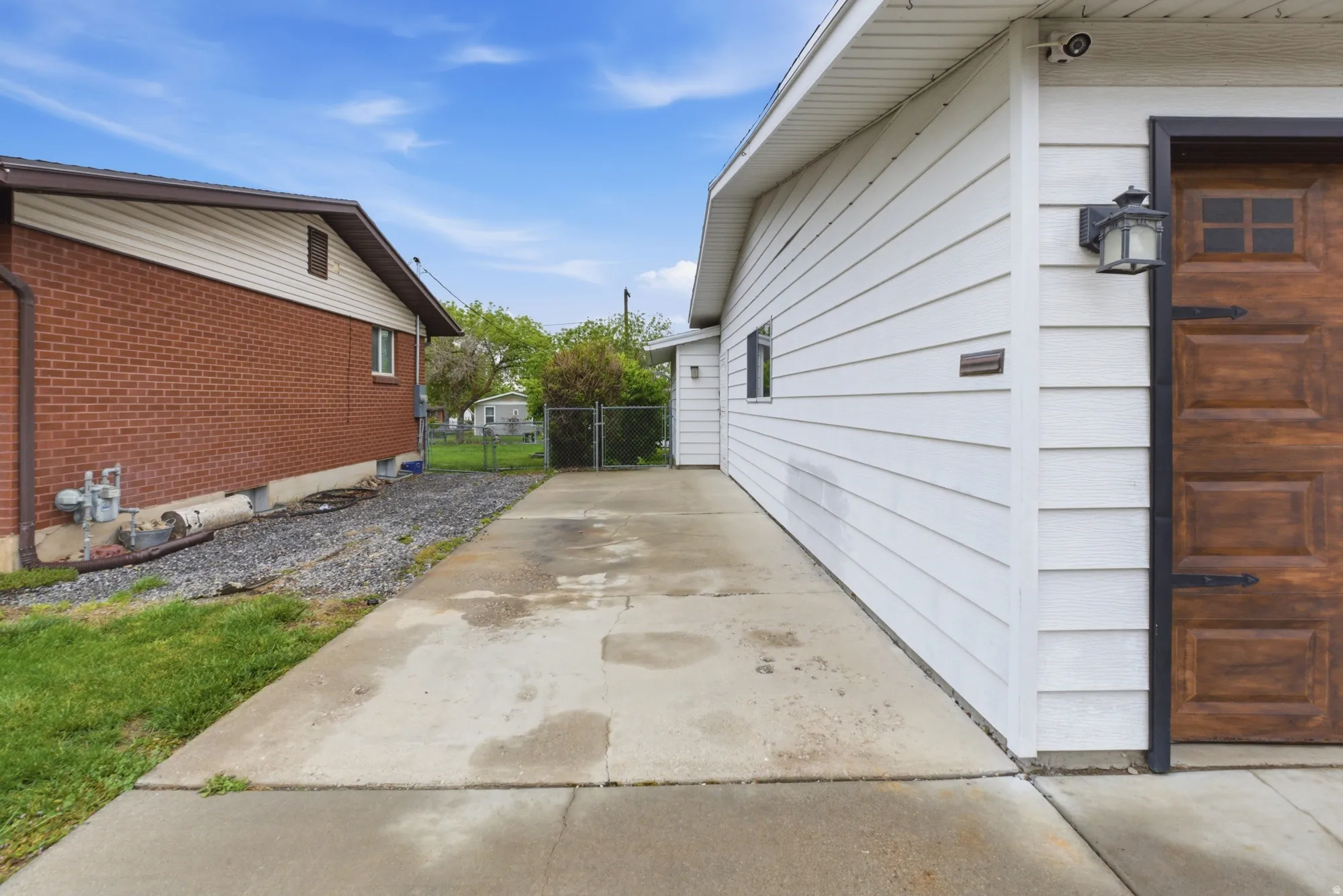 Concrete driveway alongside white horizontal siding and a wood-finish garage door with decorative hardware