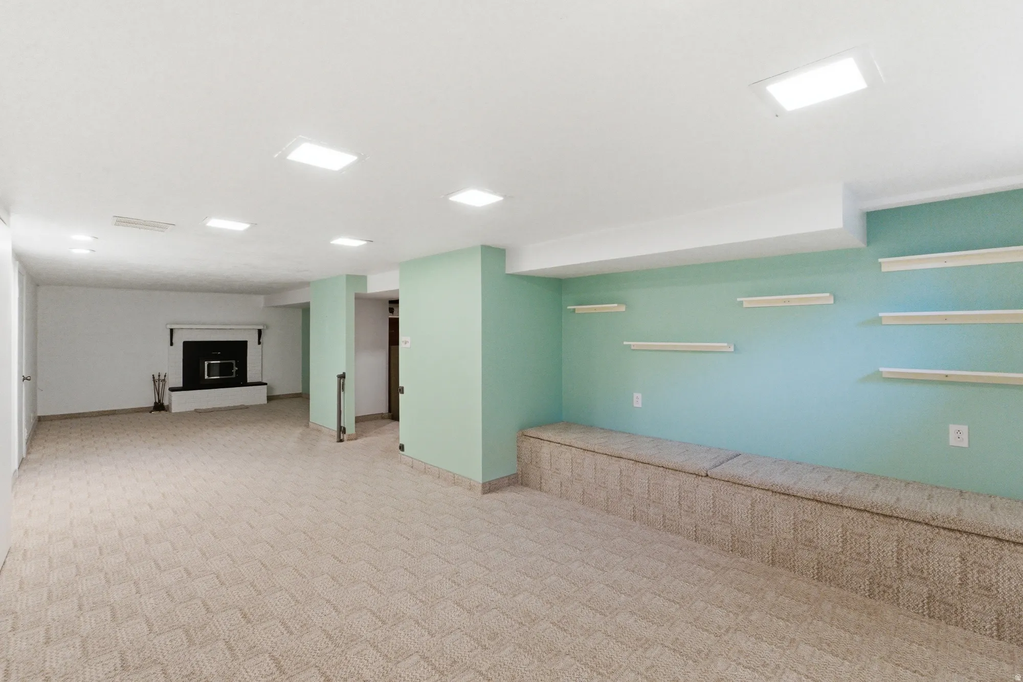 Spacious room featuring patterned carpeting, recessed lighting, and a built-in bench with integrated shelving