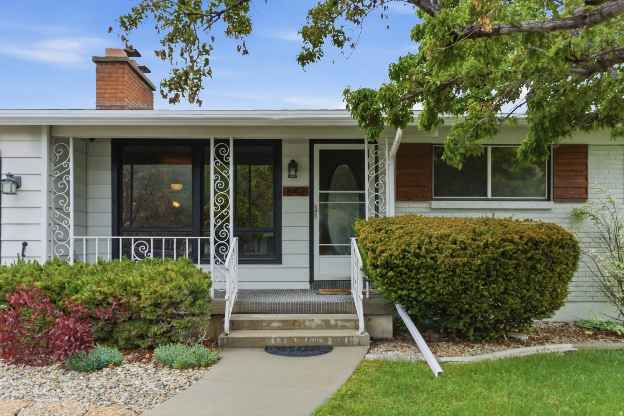 Front facade featuring white siding, a contrasting dark front door, and a concrete pathway leading to the entry