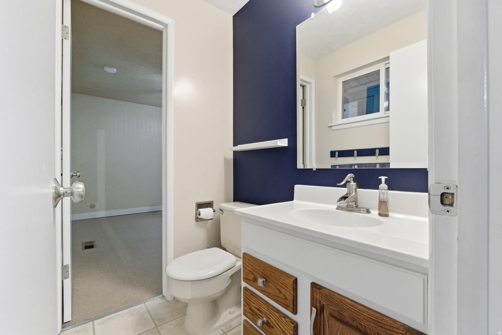 Bathroom featuring a white vanity with wood-finish drawer fronts and chrome hardware, a white undermount sink, and a chrome faucet
