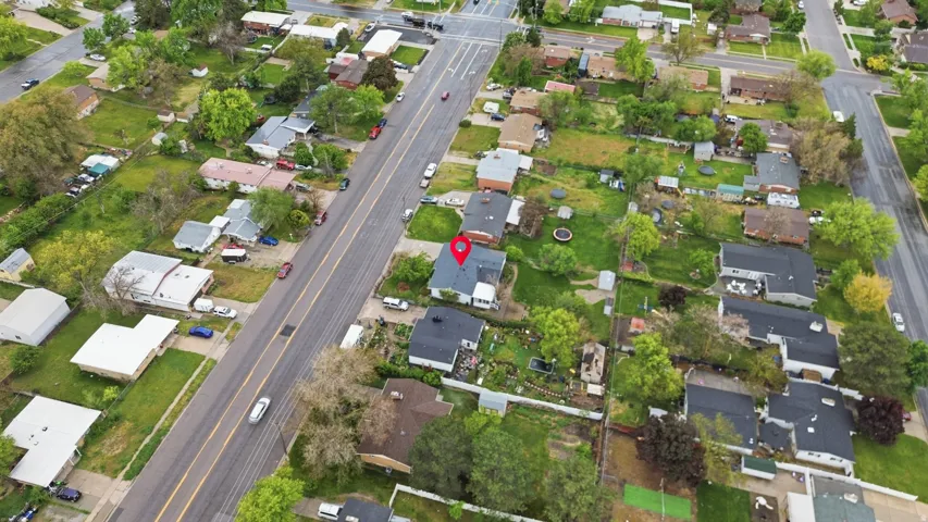 Aerial property overview featuring an asphalt shingle roof, mature perimeter trees, and a spacious backyard with green space
