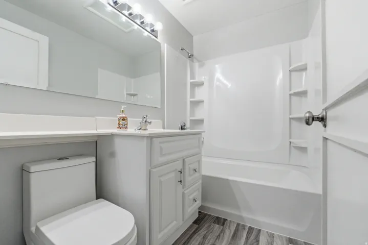 Bathroom featuring a white vanity with cabinet storage, a white countertop, and a large wall-mounted mirror