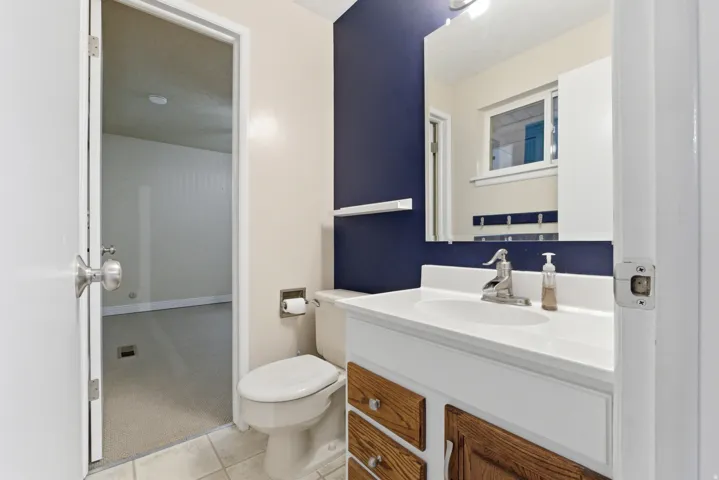 Bathroom featuring a white vanity with wood-finish drawer fronts and chrome hardware, a white undermount sink, and a chrome faucet