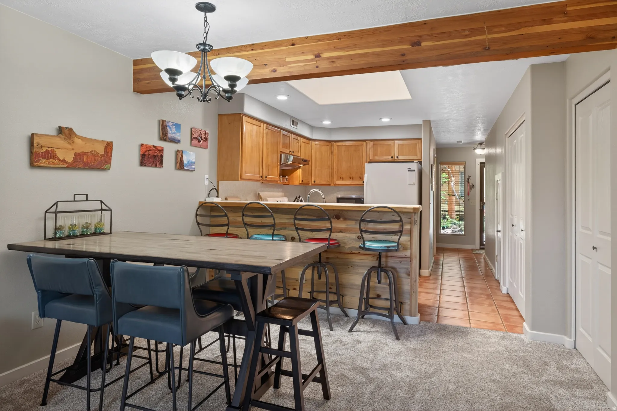 Kitchen and dining area featuring a wood beam accent, a light wood bar with a wood panel base, and wood-finish cabinetry