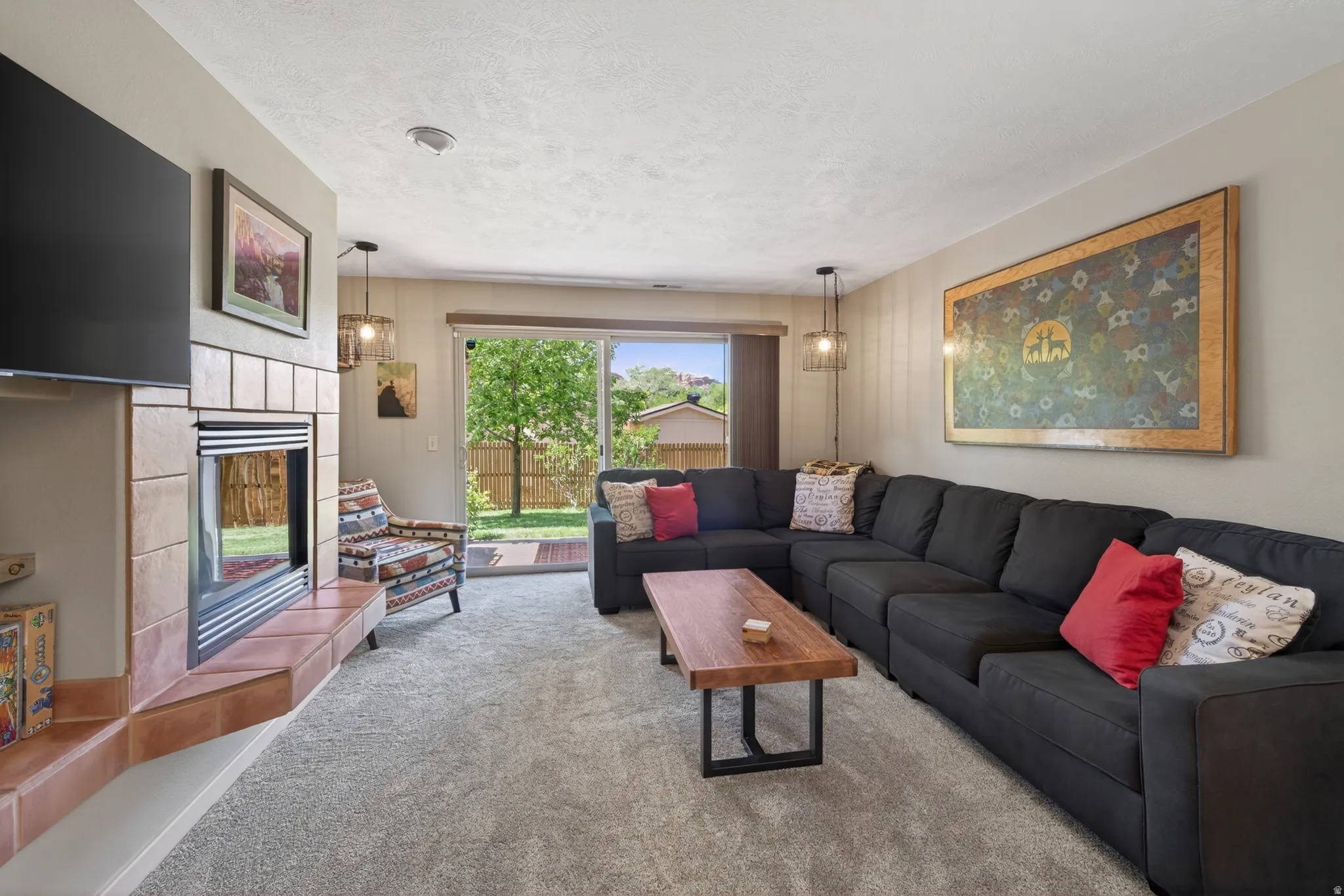 Living area featuring plush carpeting, a tiled fireplace with hearth, and a large sliding glass door