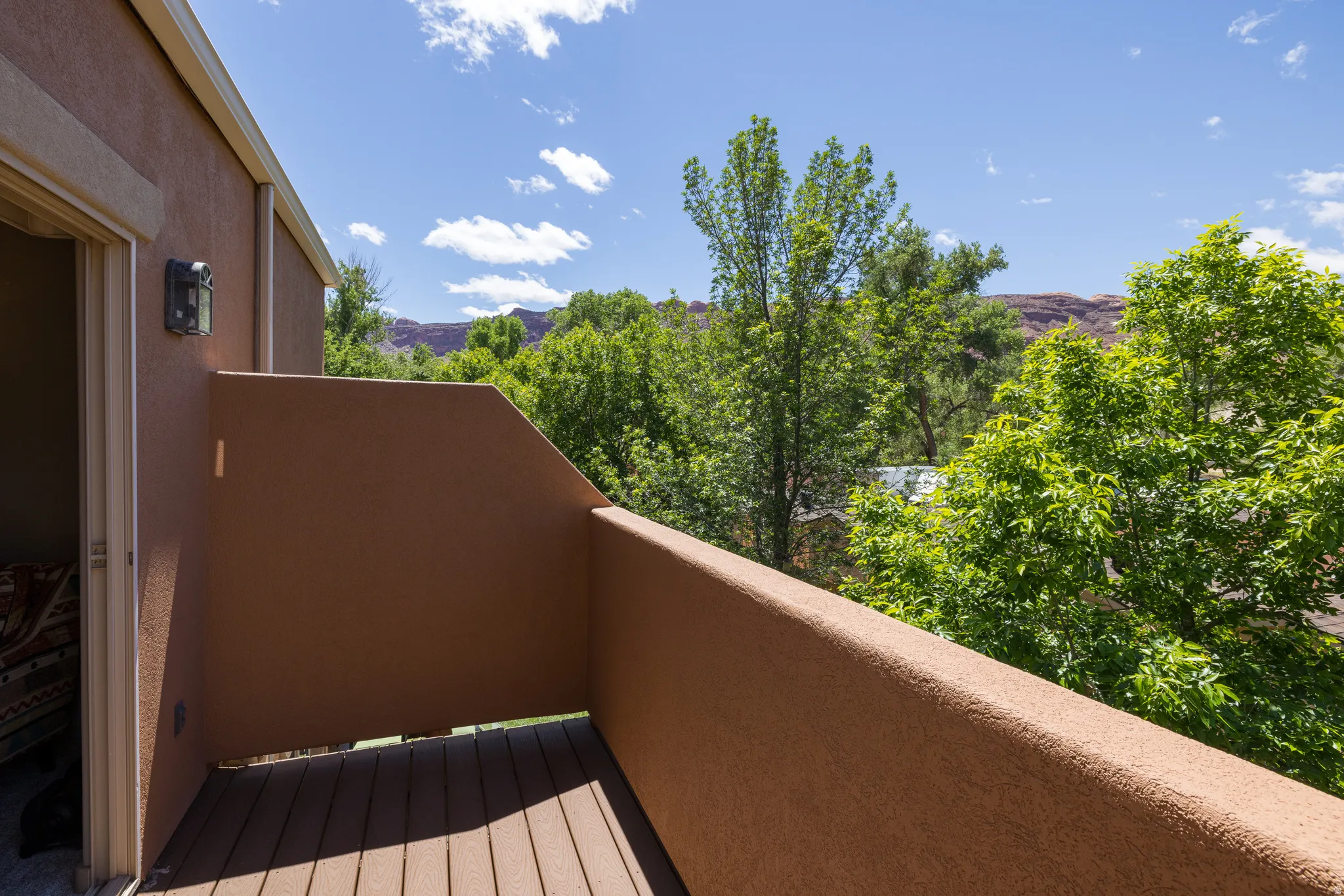 Private balcony featuring textured stucco walls and Trex flooring