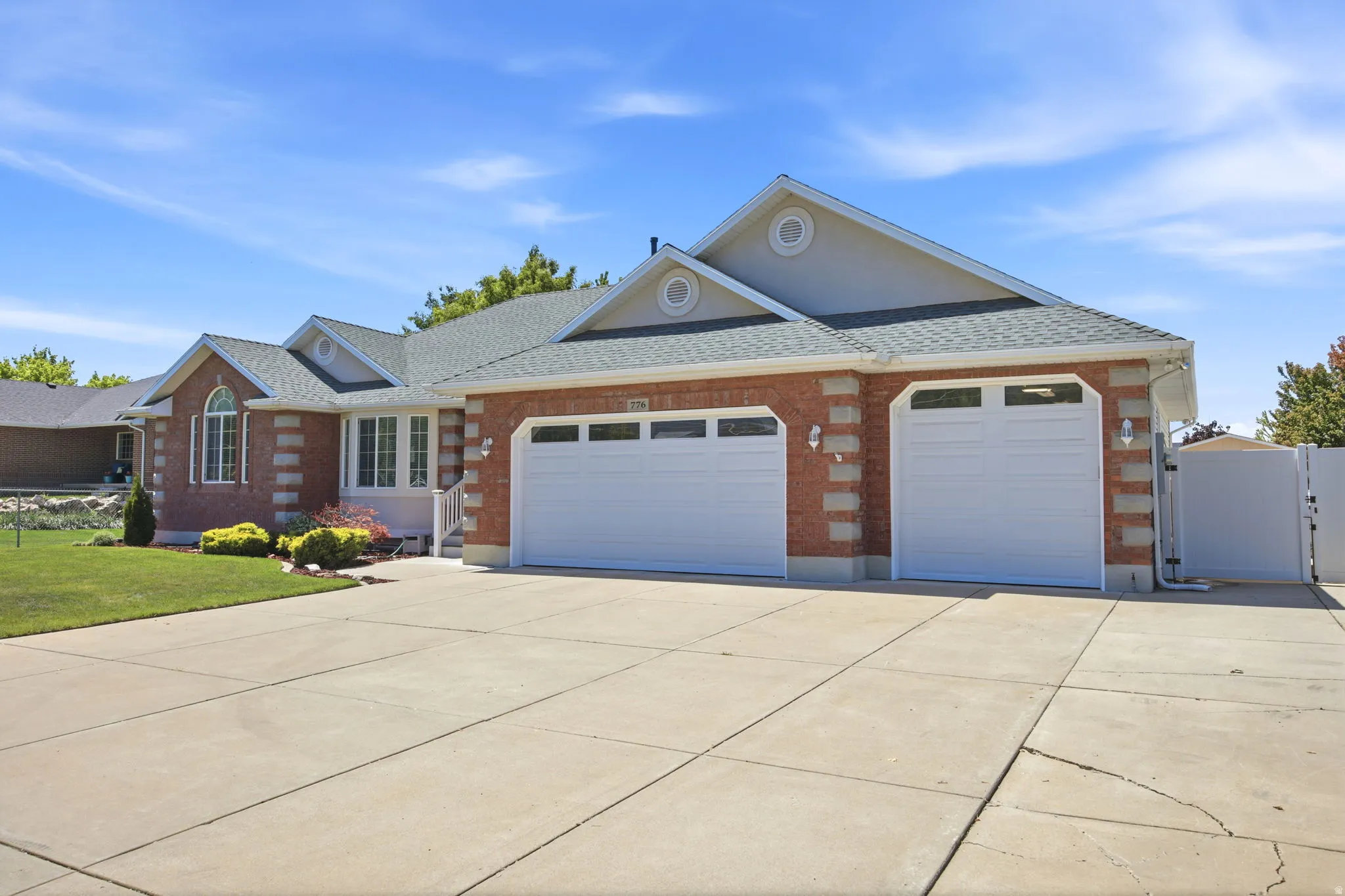 Brick facade residence featuring a multi-car garage with two white doors