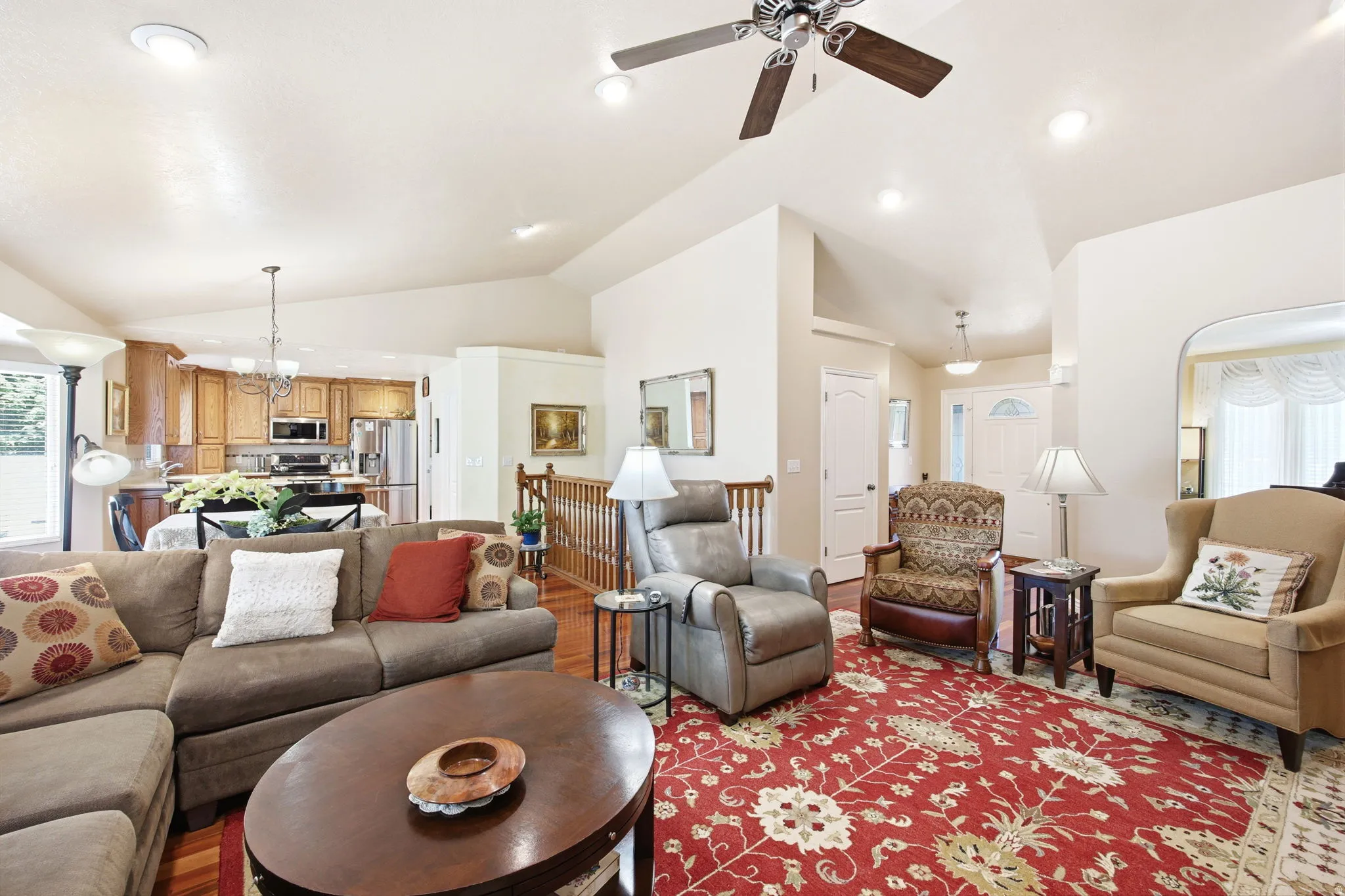 Vaulted ceilings enhance this living area featuring wood-finish flooring and recessed lighting
