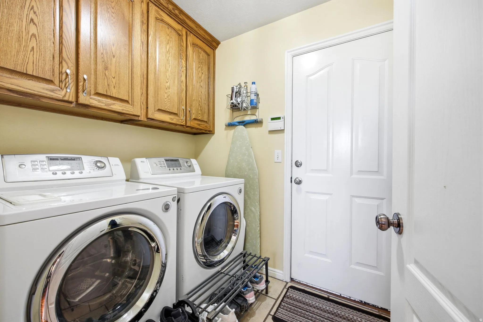 Dedicated laundry area featuring wood cabinetry, tiled flooring, and a white paneled door